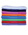 A stack of terry velour beach towels in various vibrant colours, featuring a range of shades from white to dark blue.