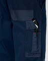 A close-up of navy blue work pants featuring multiple pockets, including a pen pocket, with visible stitching details.