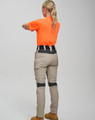 Light beige work pants featuring a stretch design and a black waistband, paired with an orange shirt. The image has a logo.