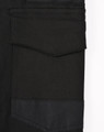 A close-up of black cotton stretch drill cuffed work pants, featuring pockets and a logo.