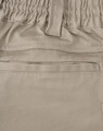 A close-up of beige unisex cotton stretch drill work shorts, featuring an elastic waistband and a pocket.