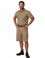 A man stands wearing khaki cargo shorts and a matching short-sleeve shirt. The outfit features pockets and a belt.