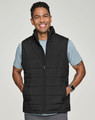 A man wearing a black insulated puffer vest with a 3D cut over a grey shirt, smiling. The vest has a logo.