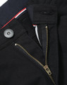 A close-up of black ladies' chino pants, featuring a zip fly, button closure, and a branded label.