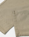 A close-up of khaki chino pants, highlighting the fabric and stitched hem. The image features a logo or branding detail.