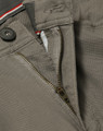 A close-up of grey chino pants showcasing a zippered fly and button closure, with a hint of contrasting interior detail.