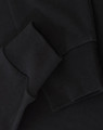 A close-up of black long-sleeve cotton tee shirt cuffs, featuring a visible logo.
