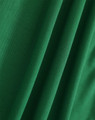 A close-up of textured green fabric, showcasing the weave and draping of the material.