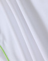 A close-up of a white polo shirt featuring a textured fabric and green detailing. The shirt has a logo.
