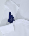A white ladies cotton stretch polo shirt featuring a collar and button placket, with a brand label inside.