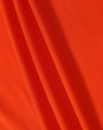A close-up of orange fabric featuring a textured surface, ideal for polo shirts. The image includes a logo.