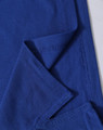 A blue polo shirt featuring a textured fabric with a folded sleeve detail and a branding logo.