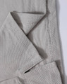 A close-up of a light grey polo shirt, showing the textured fabric and stitching details. The shirt features a logo.