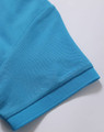 A close-up of a turquoise polo shirt sleeve, featuring a textured fabric and a logo.