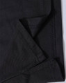 A close-up of black fabric showing the folded edge and stitching detail of a polo shirt. The fabric has a textured finish.