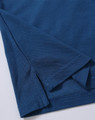 A close-up of a dark blue polo shirt featuring a folded hem and sleeve detail. The shirt has a subtle texture and branding.