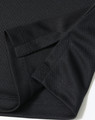 A close-up of a black sustainable jacquard knit polo shirt showcasing the fabric and sleeve design.