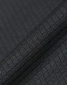 A close-up of textured black fabric, showcasing a sustainable jacquard knit pattern. Featuring a subtle sheen, it has a fabric brand logo.