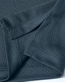 A close-up of a dark grey textured fabric showcasing the details of a sustainable knit polo shirt.