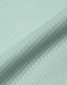 A close-up of a light mint green jacquard knit fabric with a textured pattern. The material appears soft and sustainable.