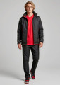 A model wears black track pants with a matching jacket and a red t-shirt, featuring a logo.