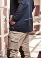 A navy unisex waterproof jacket is worn by a person with their hand in their pocket, paired with beige cargo pants.