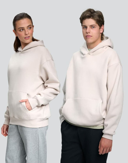 Unisex premium fleece oversized hoodie in light beige, featuring a front pocket and a hood. Logos included.