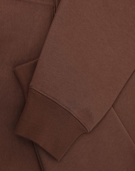 A brown unisex premium fleece oversized hoodie with ribbed cuffs and a soft finish. It features a logo.