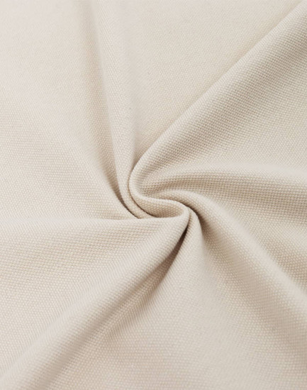 A close-up of beige cotton/polyester pique fabric, showcasing its texture and weave.