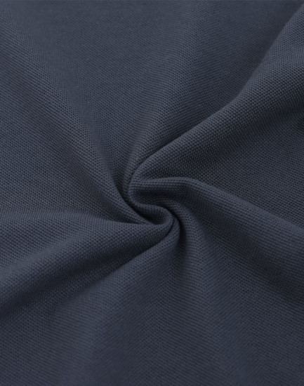 A close-up of dark navy fabric featuring a textured pique weave, highlighting its softness and quality.