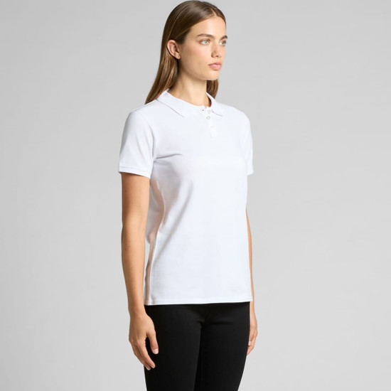 A white polo shirt with a collar and three buttons, featuring a small logo. The model stands facing to the side.