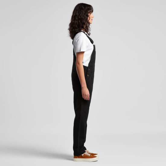 Black canvas overalls worn with a white T-shirt and brown shoes, displayed in a side view. The outfit features a logo.
