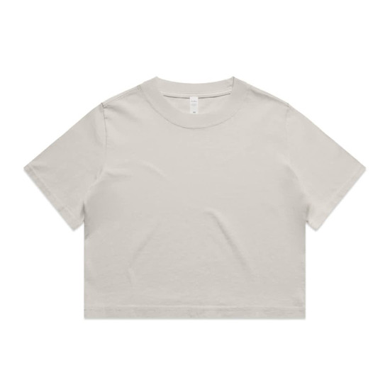 A light beige cropped t-shirt featuring short sleeves and a round neckline. The shirt has a simple design and a logo.