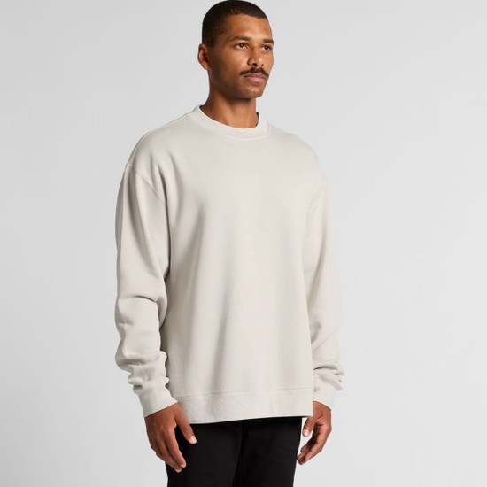 A light grey sweater on a man, featuring a relaxed fit and long sleeves. The garment has a logo on it.