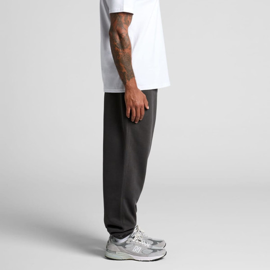 Faded grey track pants featured on a model, paired with a white t-shirt and grey sneakers. The pants have a logo.
