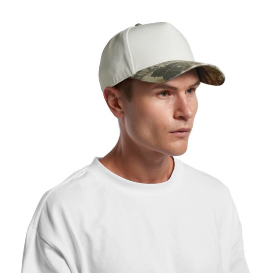 A white cap with a camo-patterned peak, featuring a logo on the front, worn by a model.