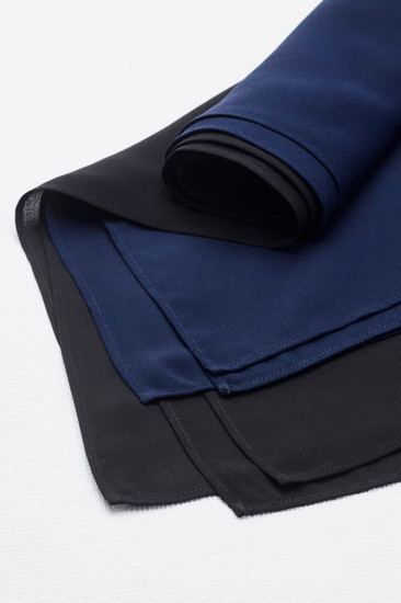 A folded women's hijab featuring layers in navy blue and black, showcasing a smooth fabric texture.