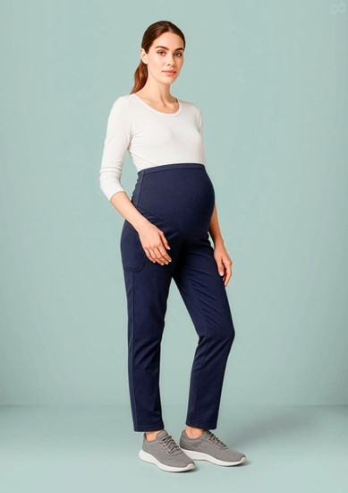 A pregnant model wearing navy maternity scrub pants paired with a light-coloured top and grey shoes.