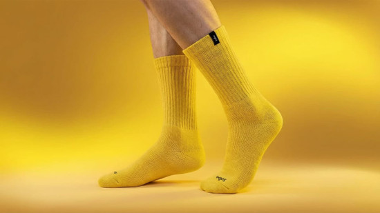 Yellow heavy cotton workwear socks displayed on a model's feet against a yellow background, featuring a small logo.
