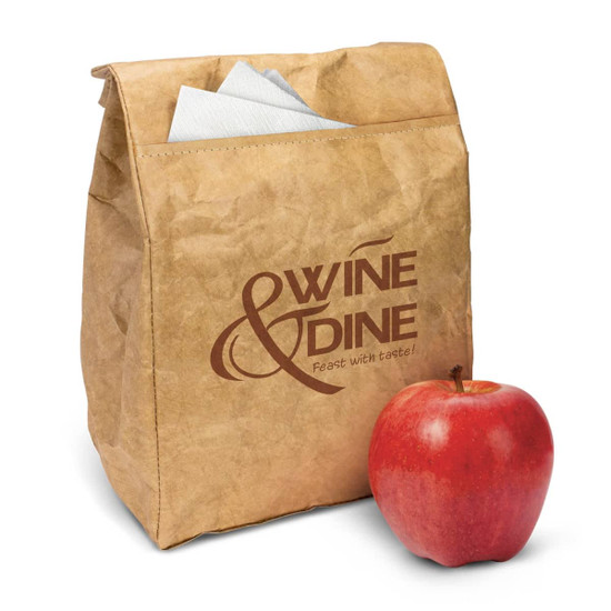 A brown paper lunch bag with a logo and an apple beside it. The bag includes folded napkins inside.