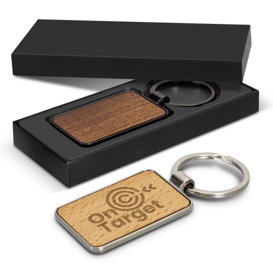 A rectangular key ring with a wooden finish, presented in a black gift box. Features a logo on one side.