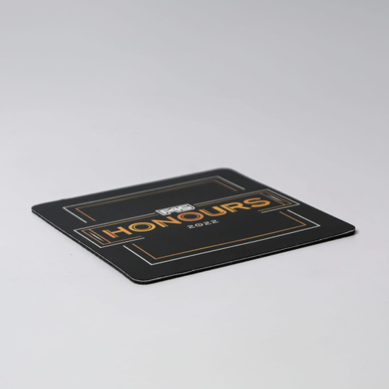 A black deluxe coaster featuring gold accents and a logo, with the word "Honours" prominently displayed.