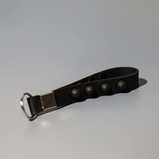 A black key chain stress reliever with popper buttons and a silver attachment ring.