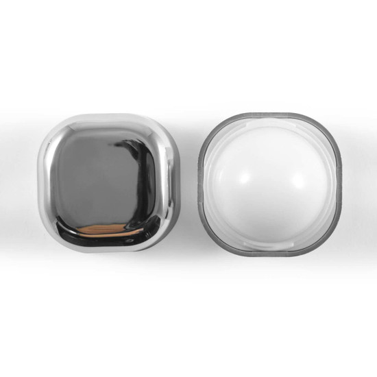 A cubic lip balm container with a shiny metallic exterior and a smooth, white balm inside.