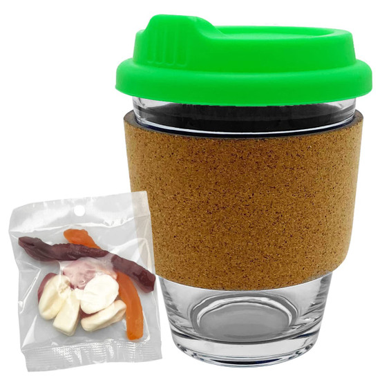A glass coffee cup with a cork band and a green lid, accompanied by a pack of mixed lollies.