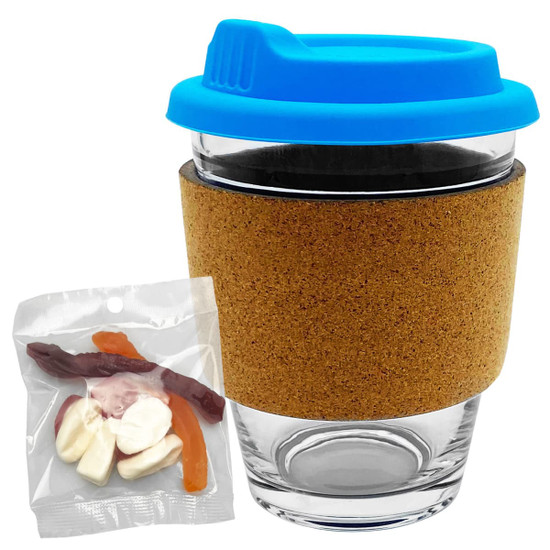 A glass coffee cup with a cork band and a blue lid, accompanied by a packet of mixed lollies in various colours.