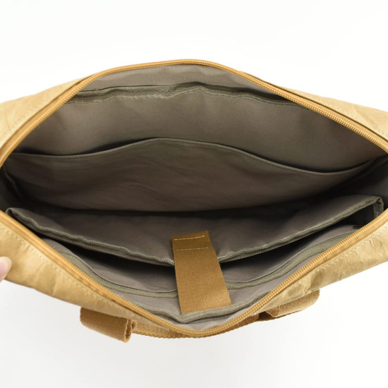 An interior view of a tan kraft paper business satchel with compartments and a zip closure. It features a soft lining.