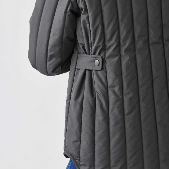 A thermal jacket in dark grey with quilted texture and button detail on the sleeve. It features a relaxed fit.