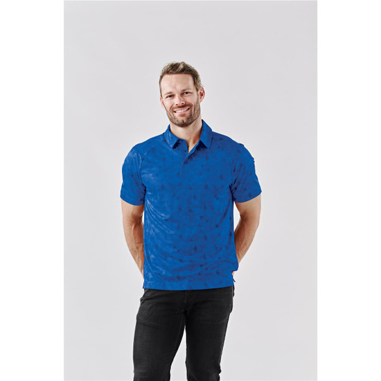 A blue polo shirt with a subtle pattern, featuring a collar and short sleeves, worn by a man smiling.