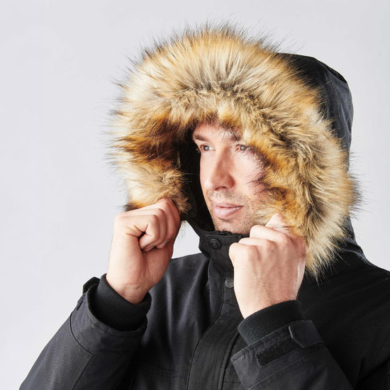 A black parka jacket featuring a fur-lined hood, worn by a man adjusting the hood around his face.